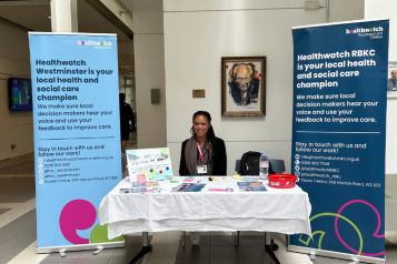 Picture of healthwatch staff member at chelsea and westminster hospital with banners explaining the role of healthwatch.